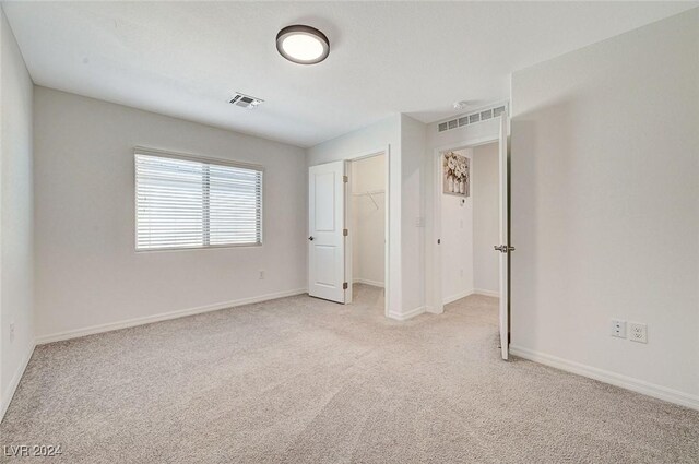 unfurnished bedroom with light colored carpet, a spacious closet, and a closet