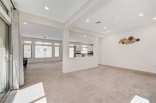 unfurnished living room with beam ceiling and light colored carpet