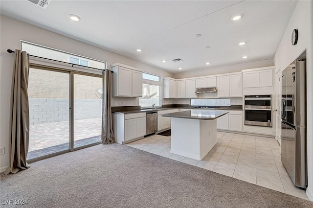 kitchen with a kitchen island, light colored carpet, white cabinetry, and stainless steel appliances