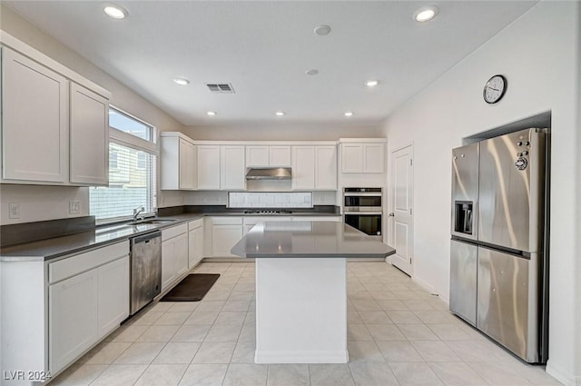 kitchen with a kitchen island, light tile patterned flooring, white cabinetry, and stainless steel appliances