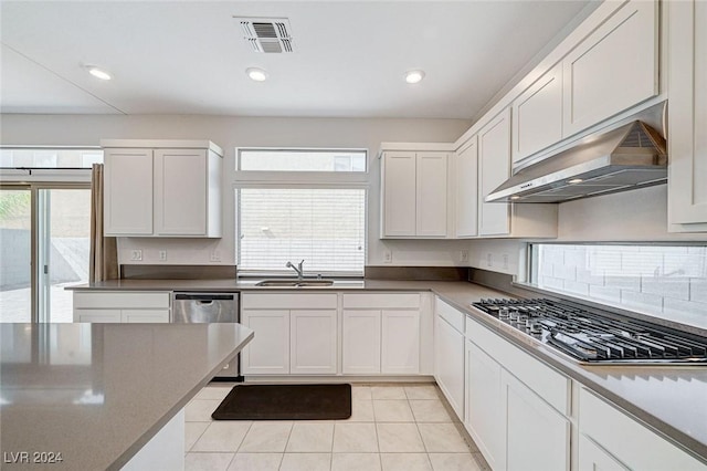 kitchen with light tile patterned flooring, white cabinets, exhaust hood, and appliances with stainless steel finishes