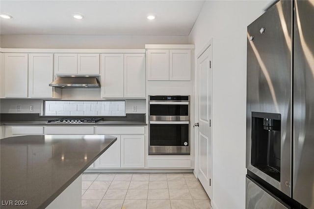 kitchen with decorative backsplash, white cabinetry, light tile patterned floors, and stainless steel appliances