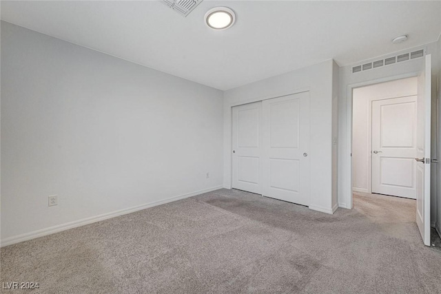 unfurnished bedroom with a closet and light colored carpet