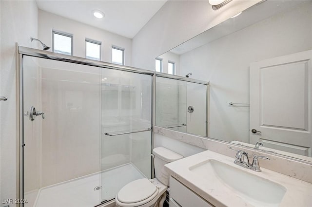 bathroom featuring vanity, toilet, and a shower with shower door