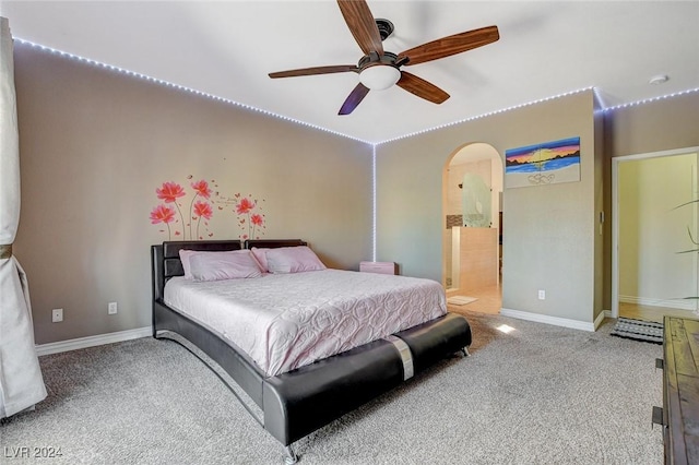 carpeted bedroom with ensuite bathroom and ceiling fan