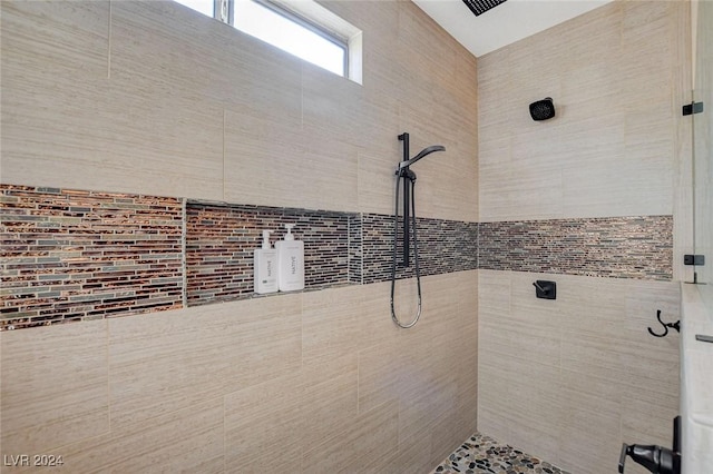 bathroom with a tile shower and tile walls