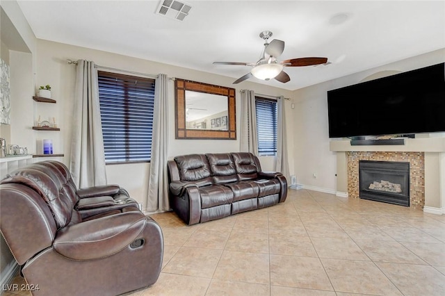 living room featuring a fireplace, light tile patterned floors, and ceiling fan