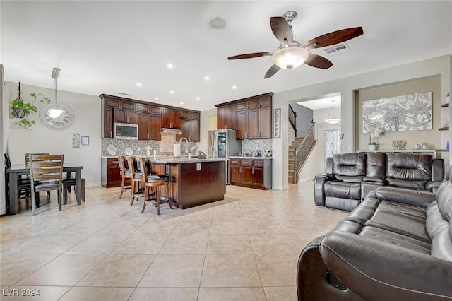 tiled living room with ceiling fan and sink