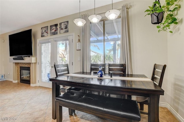 dining space featuring light tile patterned floors, a tile fireplace, and french doors