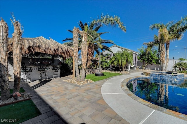 view of pool with exterior bar, an in ground hot tub, and a patio area