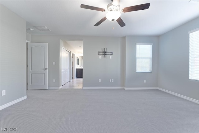 carpeted empty room featuring a wealth of natural light and ceiling fan