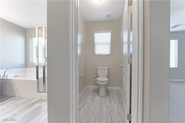 bathroom with a healthy amount of sunlight, shower with separate bathtub, and toilet