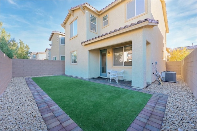 rear view of property with a lawn and central air condition unit