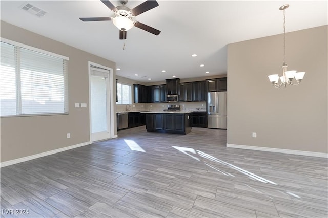 interior space featuring pendant lighting, a center island, a healthy amount of sunlight, and appliances with stainless steel finishes