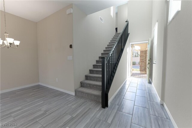 stairs with plenty of natural light and a notable chandelier