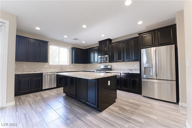 kitchen with light stone counters, sink, a kitchen island, and appliances with stainless steel finishes