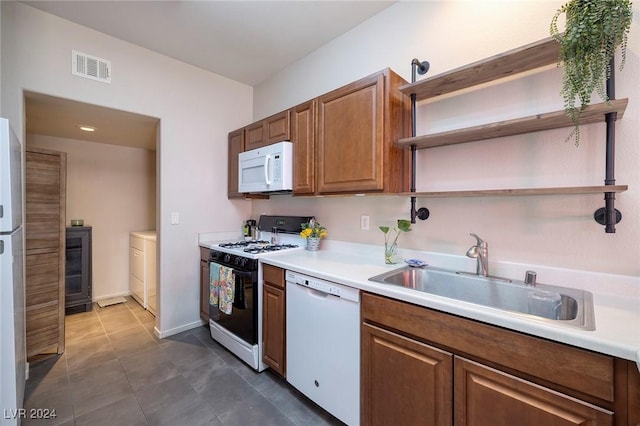 kitchen with sink, dark tile patterned flooring, and white appliances