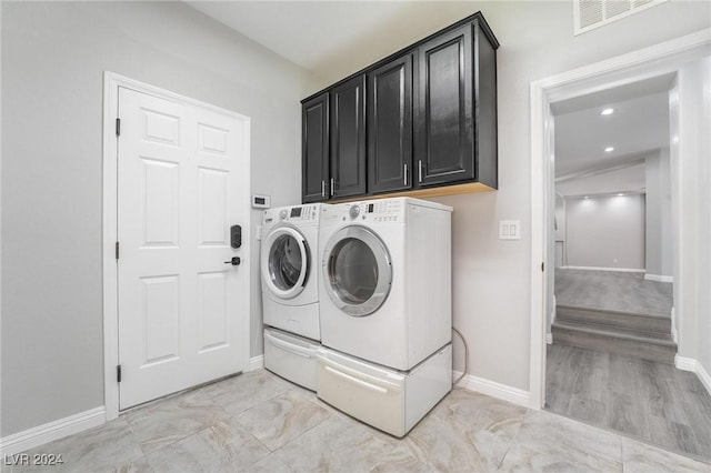 clothes washing area featuring cabinets and washer and clothes dryer