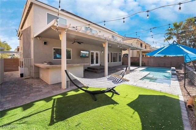 rear view of house with a patio, a lawn, ceiling fan, a fenced in pool, and an outdoor bar