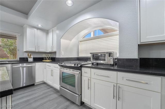 kitchen featuring stainless steel appliances, white cabinetry, and light hardwood / wood-style floors