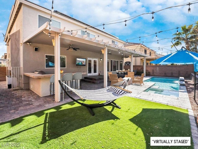 back of house featuring an outdoor bar, a patio, a yard, and a fenced in pool