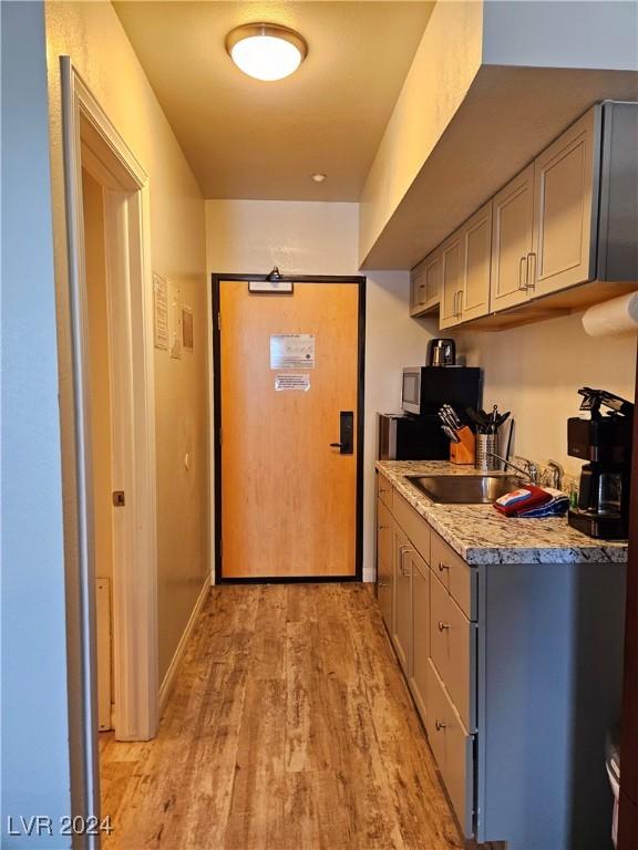 kitchen featuring gray cabinetry, light stone countertops, sink, and light hardwood / wood-style floors