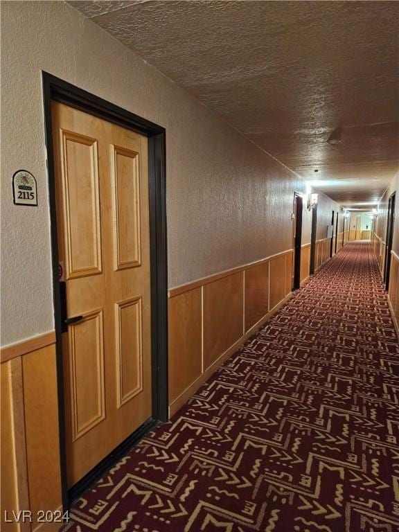 hallway with wood walls and a textured ceiling