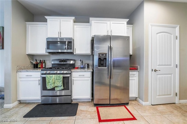 kitchen featuring white cabinetry, light tile patterned floors, light stone counters, and appliances with stainless steel finishes