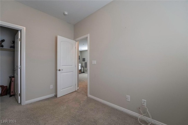 unfurnished bedroom with light carpet, a spacious closet, and a closet