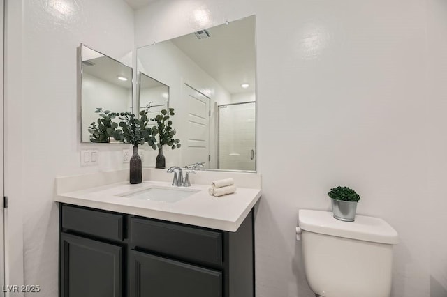 bathroom featuring toilet, a shower with shower door, and vanity