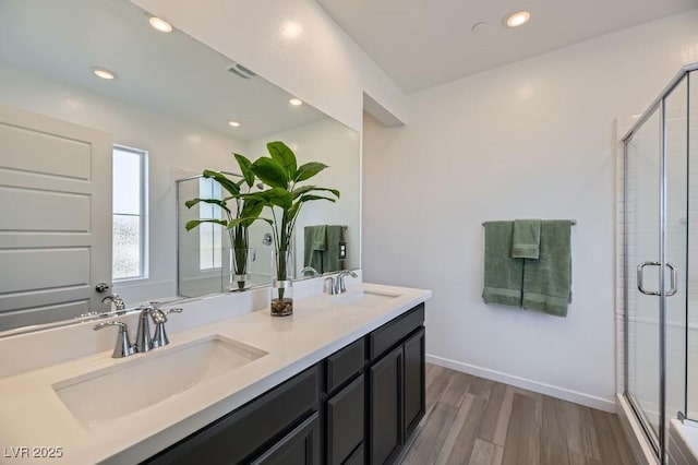 bathroom with hardwood / wood-style floors, a shower with door, and vanity