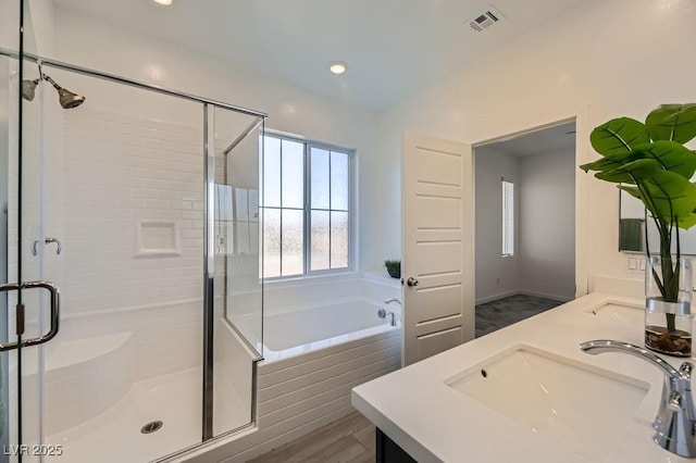 bathroom with independent shower and bath, hardwood / wood-style flooring, and vanity