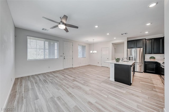 kitchen with visible vents, open floor plan, light countertops, range, and stainless steel fridge