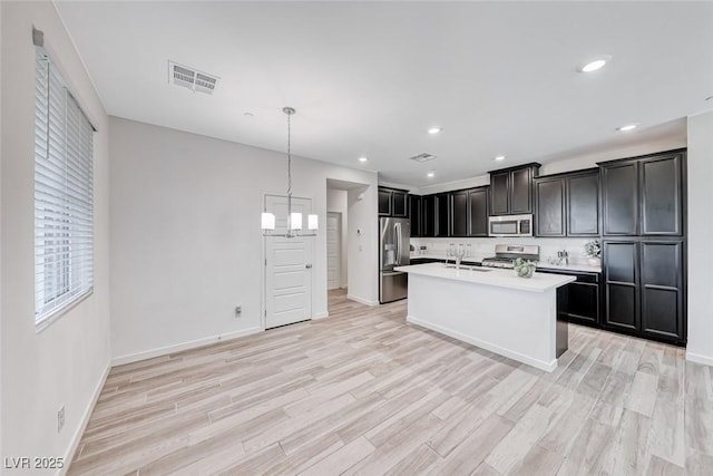 kitchen featuring light countertops, appliances with stainless steel finishes, light wood-type flooring, and visible vents