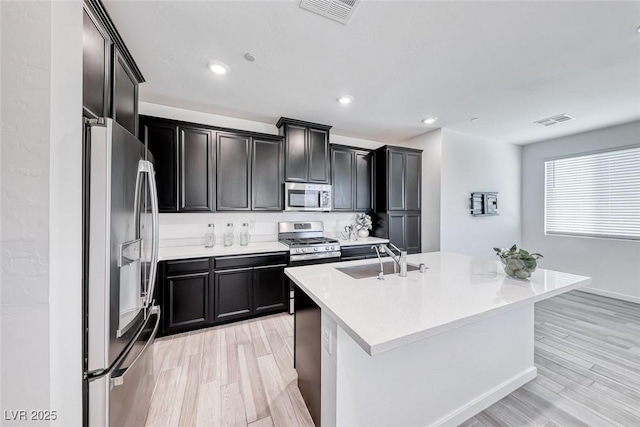 kitchen with stainless steel appliances, light wood-style flooring, a sink, and visible vents