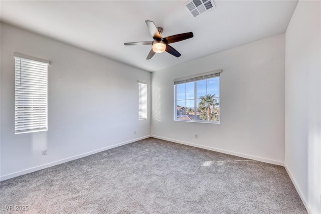 carpeted spare room featuring baseboards, visible vents, and ceiling fan