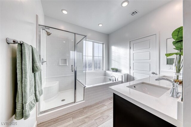 bathroom featuring visible vents, a garden tub, wood tiled floor, a shower stall, and recessed lighting