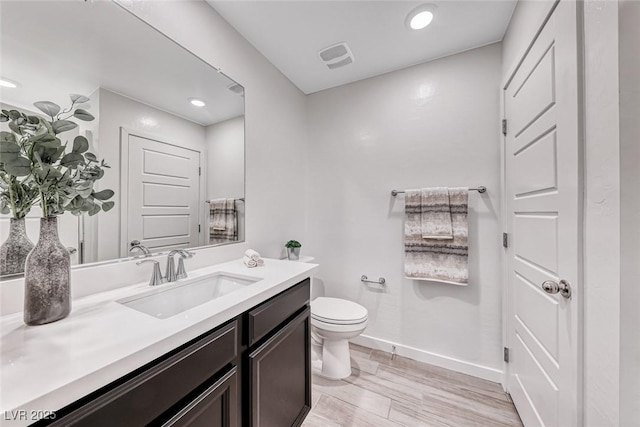 bathroom with recessed lighting, toilet, vanity, wood finished floors, and baseboards