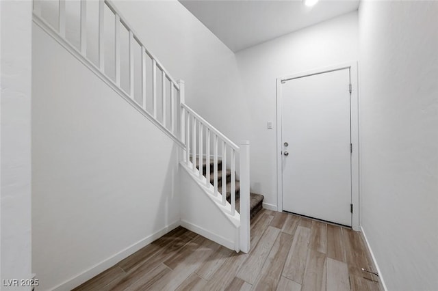 foyer with baseboards, stairway, and light wood finished floors