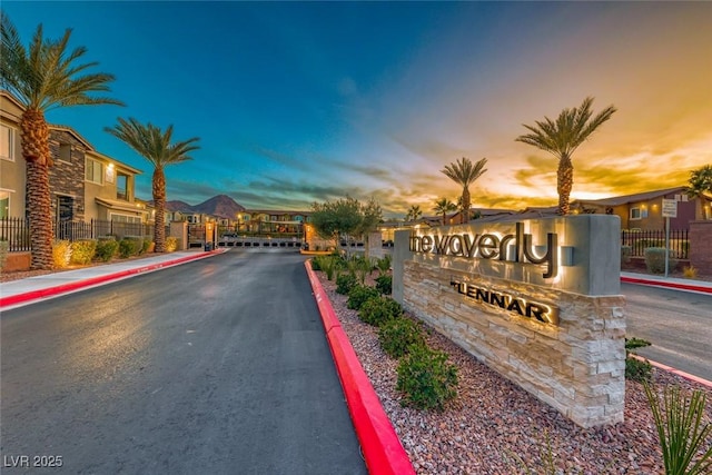 view of street with curbs, sidewalks, and a gated entry