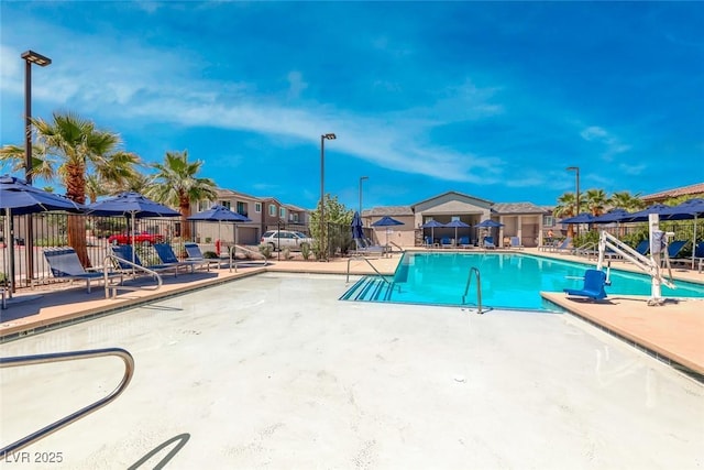 community pool featuring a patio, fence, and a residential view