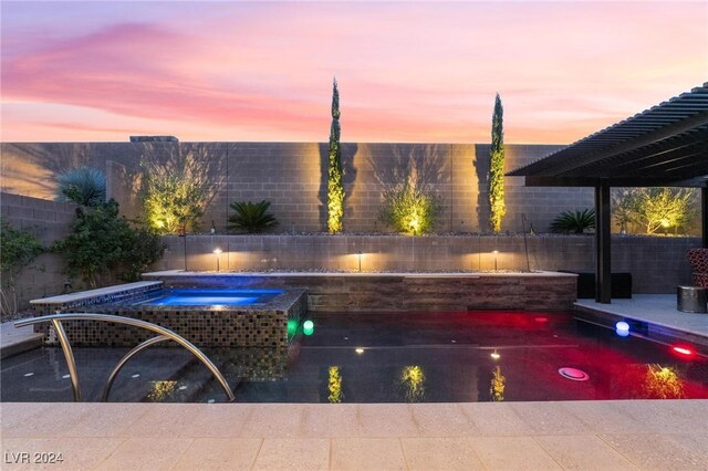 pool at dusk featuring an in ground hot tub