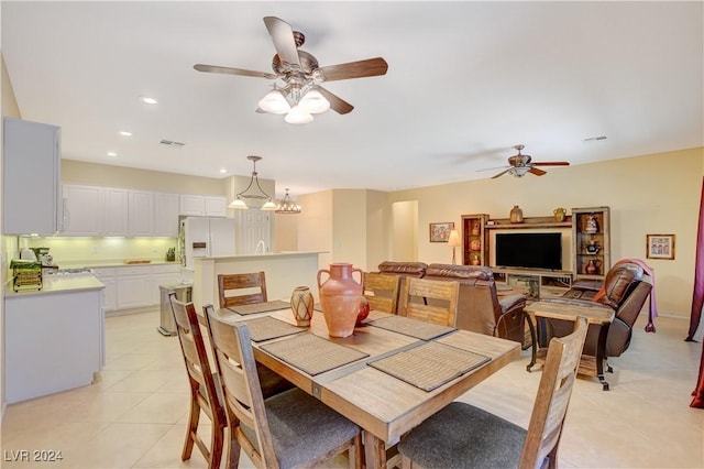 tiled dining room featuring ceiling fan with notable chandelier