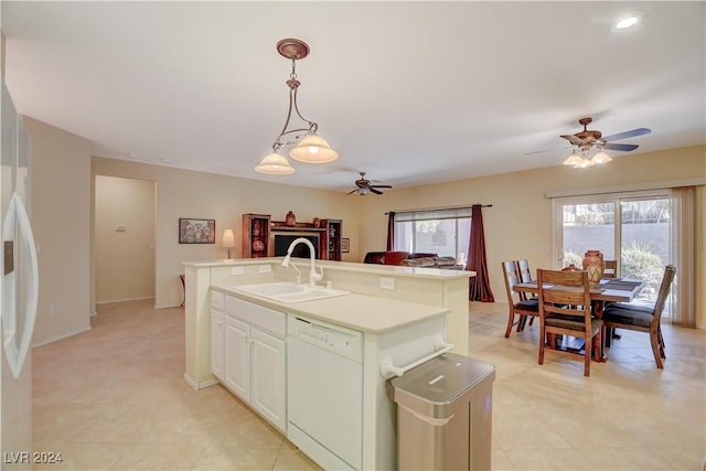 kitchen featuring decorative light fixtures, white dishwasher, a kitchen island with sink, and sink