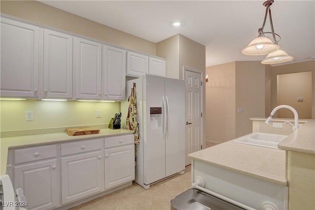 kitchen with sink, white refrigerator with ice dispenser, pendant lighting, light tile patterned floors, and white cabinets