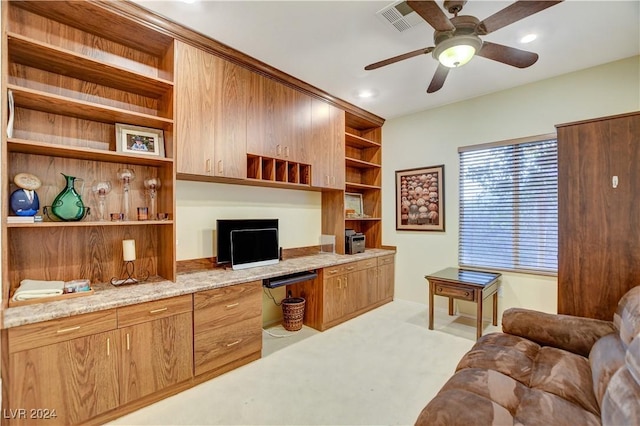 office area with ceiling fan, built in desk, and light carpet