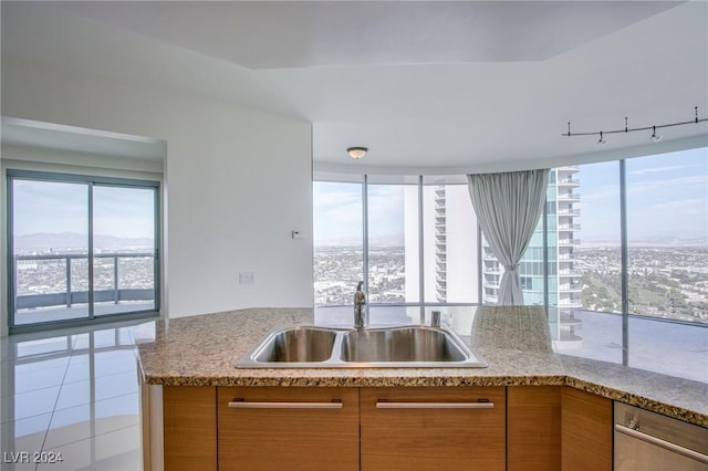 kitchen featuring light stone countertops, tile patterned flooring, and sink