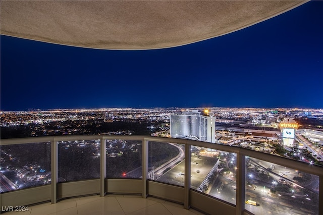 balcony at night featuring a view of city lights