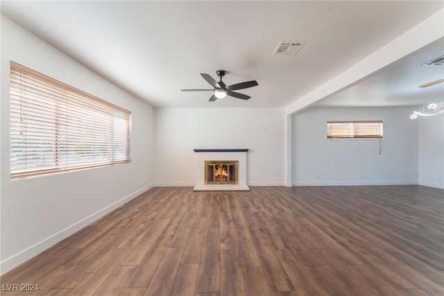 unfurnished living room featuring dark hardwood / wood-style floors, a brick fireplace, plenty of natural light, and ceiling fan