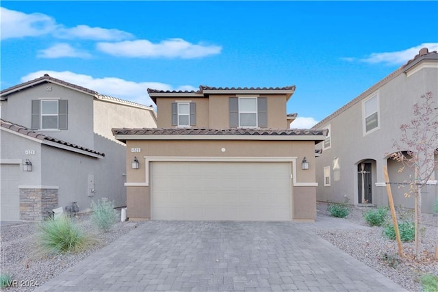 mediterranean / spanish house featuring a garage, decorative driveway, a tiled roof, and stucco siding